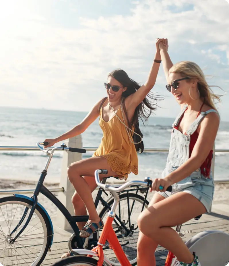 2 girls riding a bicycle while holding hands