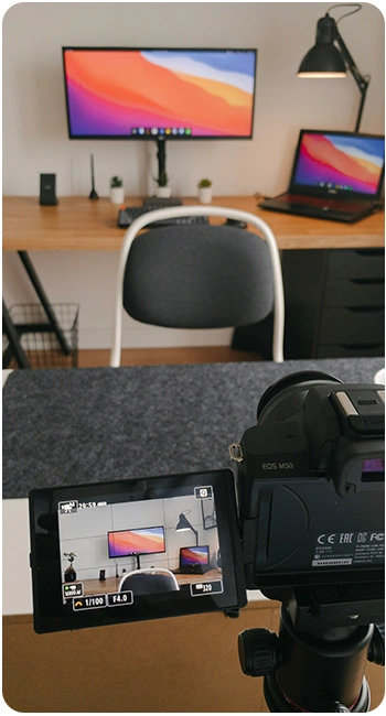 A camera on a tripod focused on a home office setup.