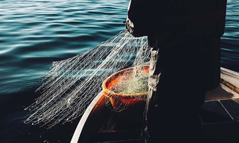 a man holding a fishing net in a boat.