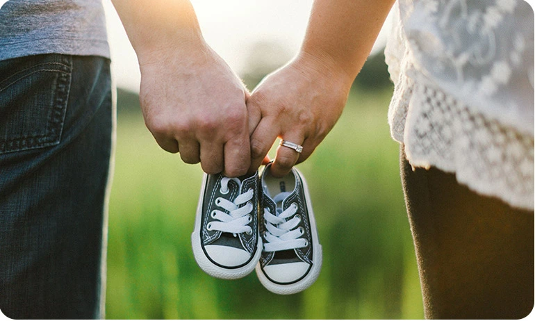 Close-up of a couple holding baby shoes between them.